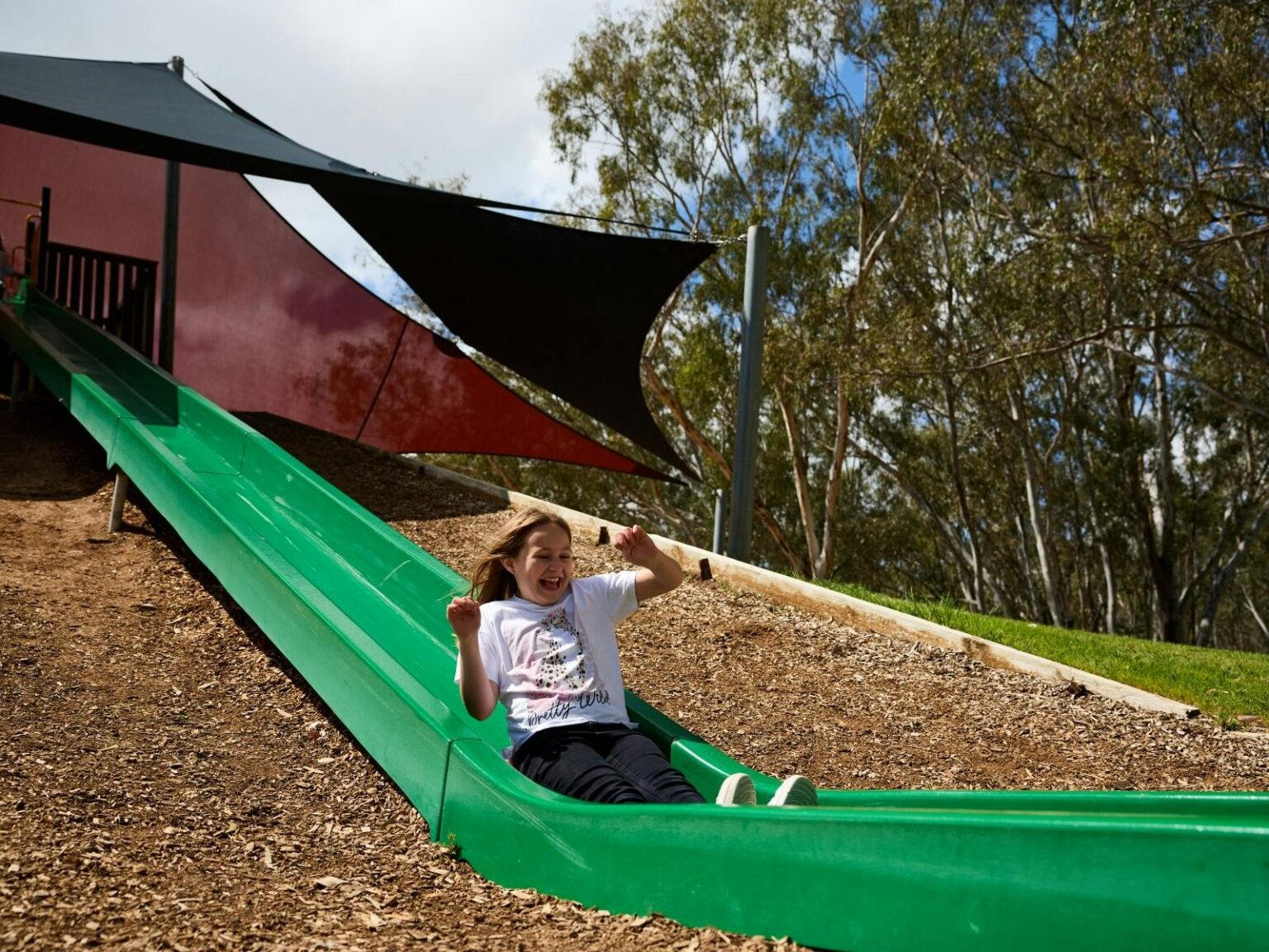girl sliding down large green slide