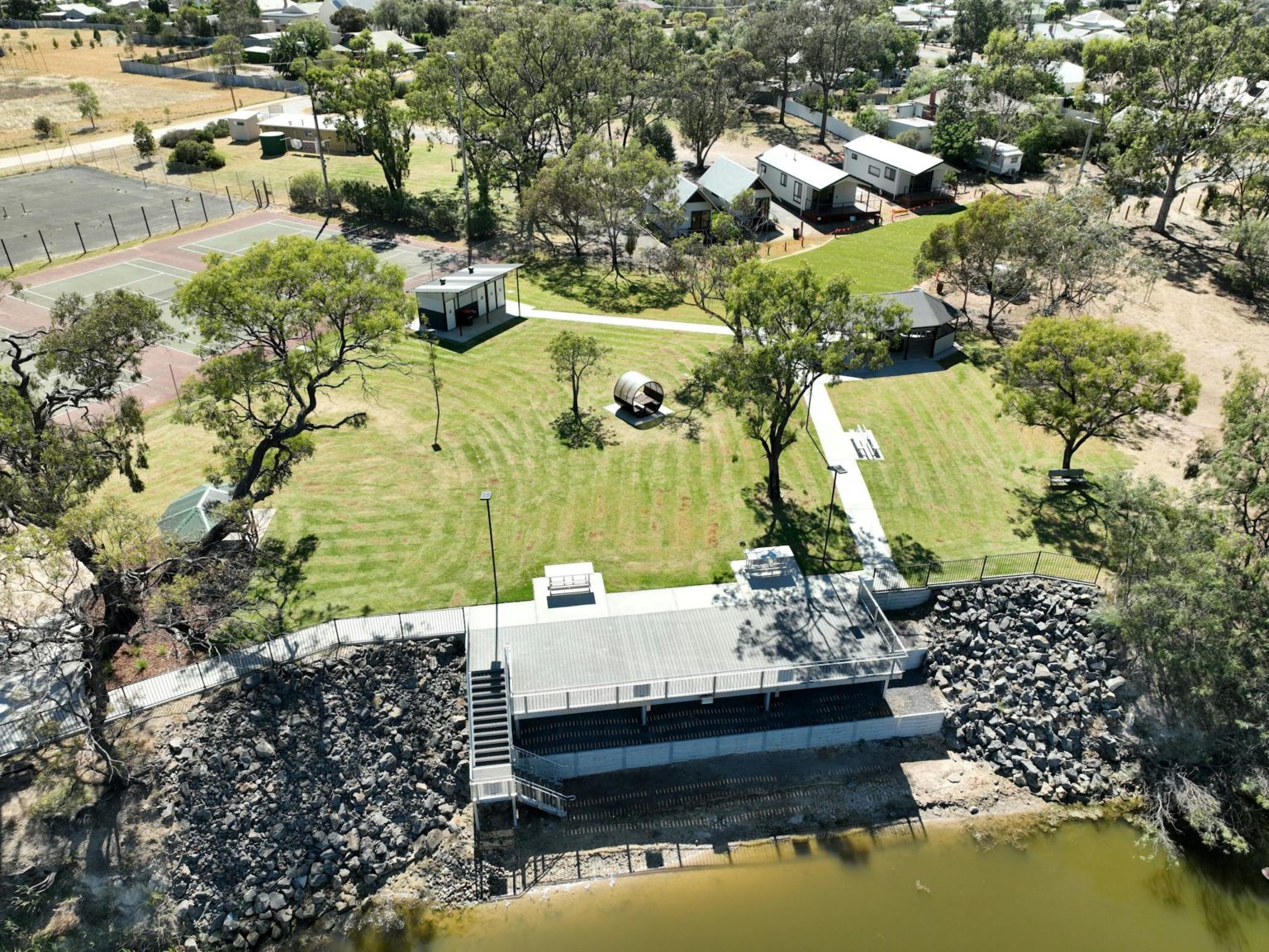 aerial view of river with grassed picnic area with cabins in background