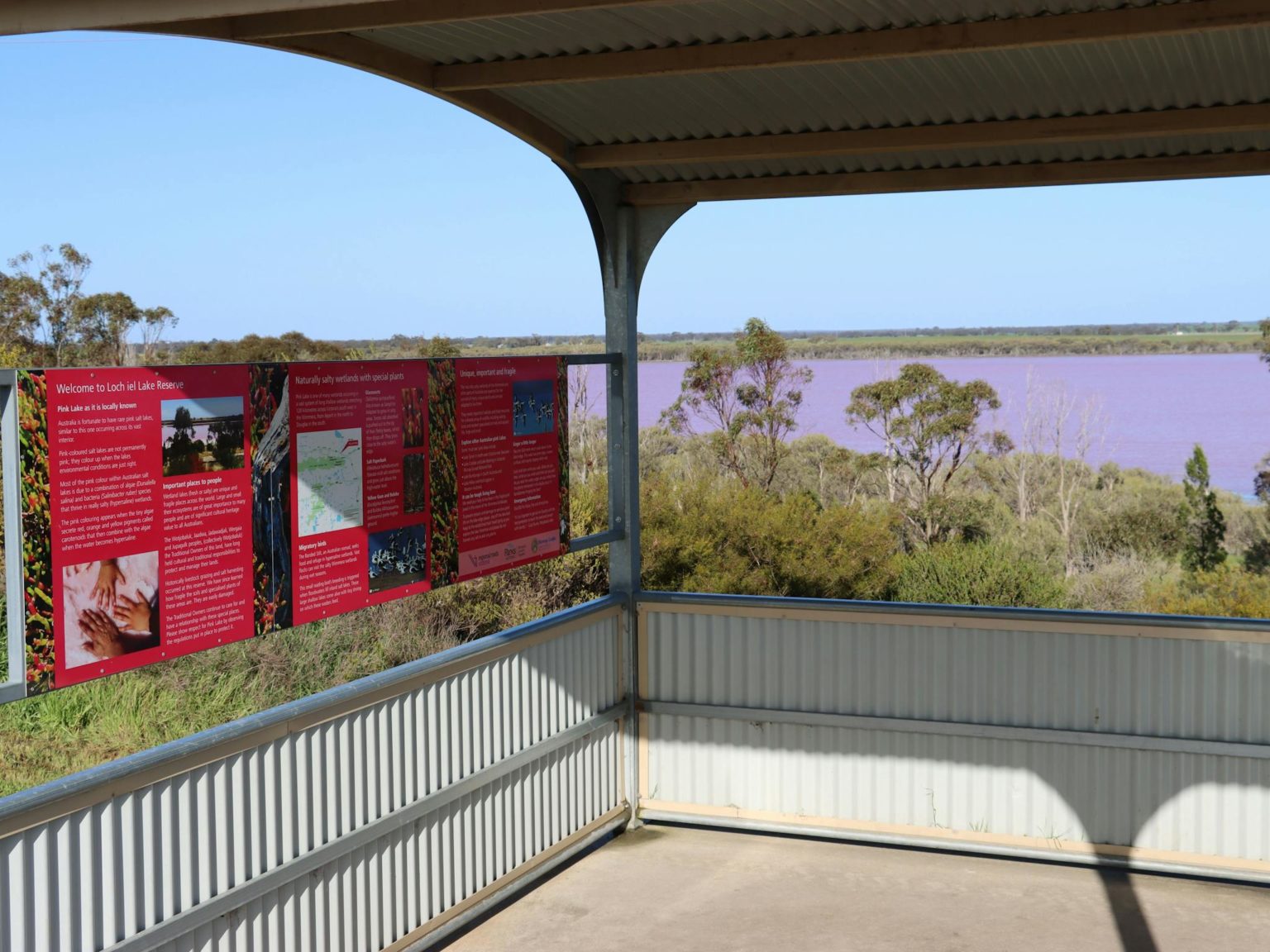 lookout shelter with interpretive signage with pink lake in background