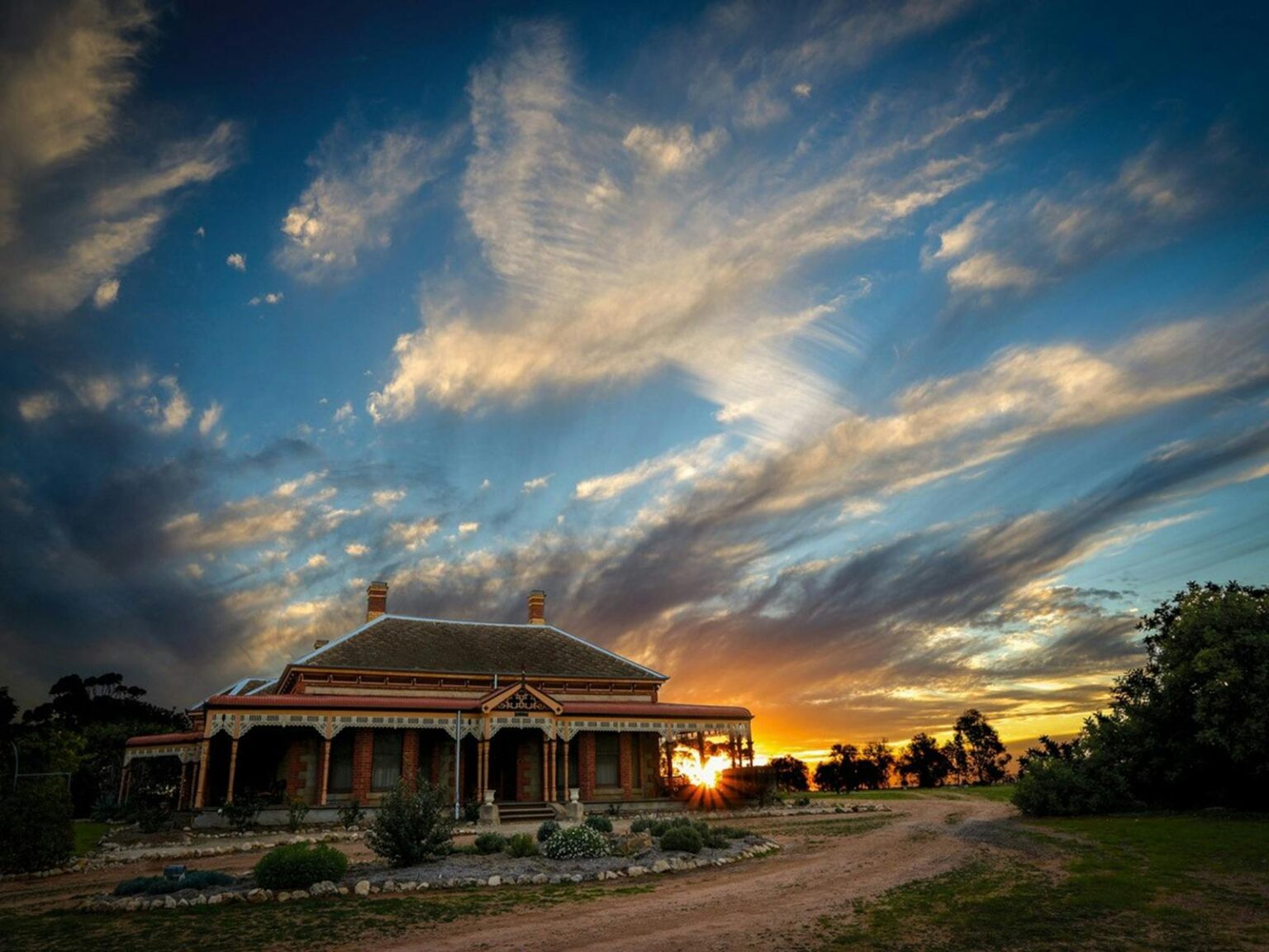 colourful sunset with old homestead and gardens in foreground