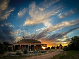 colourful sunset with old homestead and gardens in foreground