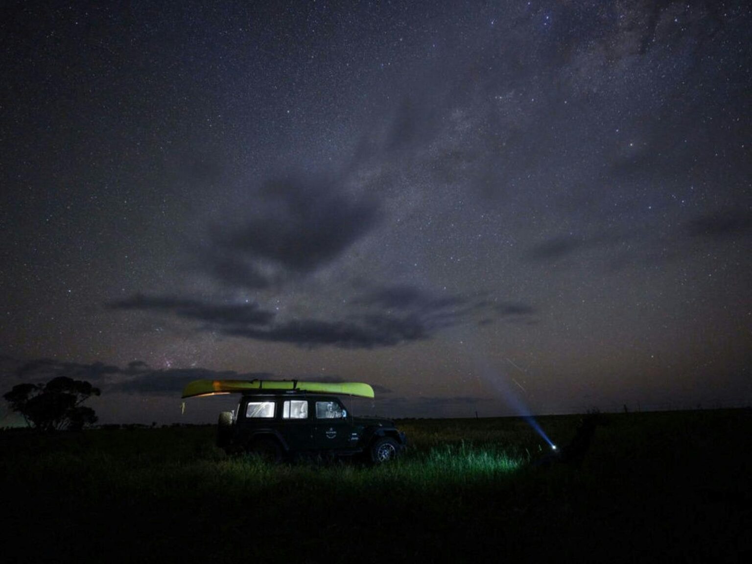 Small SUV with light on with the night sky as a backdrop