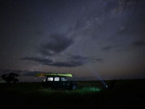 Small SUV with light on with the night sky as a backdrop
