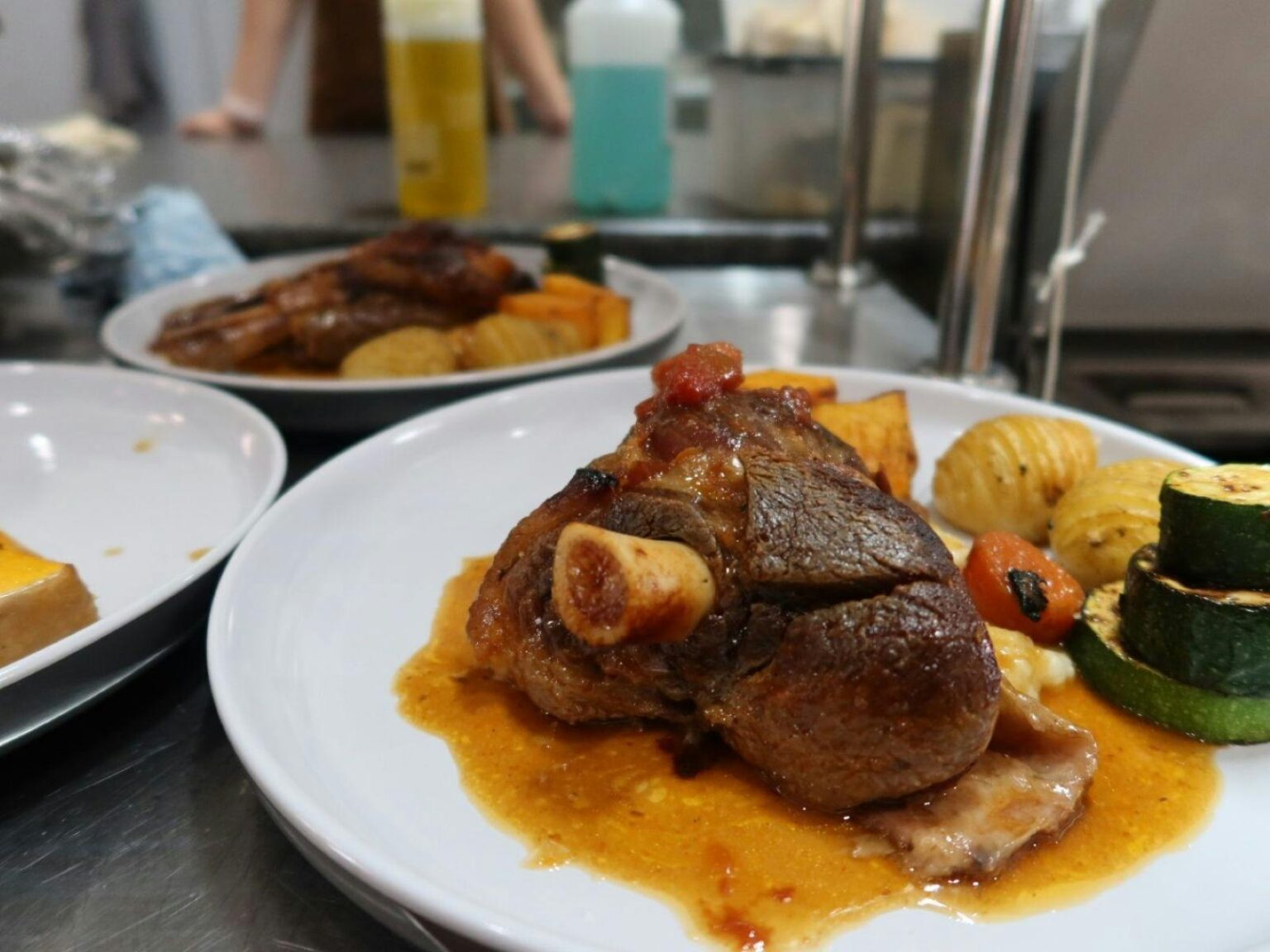 Plates of lamb shanks and vegetables on a large table