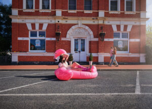 Woman sitting on an inflatable flamingo in the street