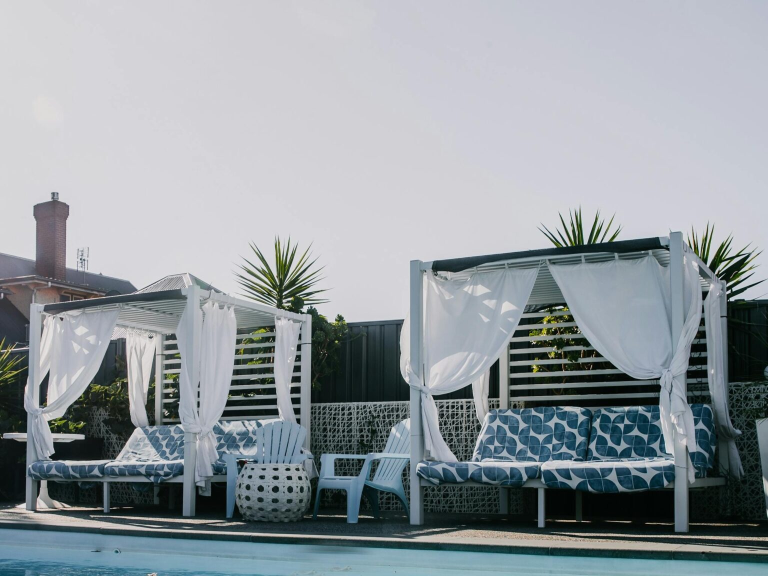 Relaxing poolside beds Day beds by sparkling blue pool water.