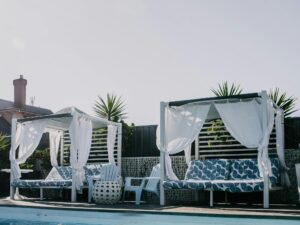 Day beds by sparkling blue pool water.