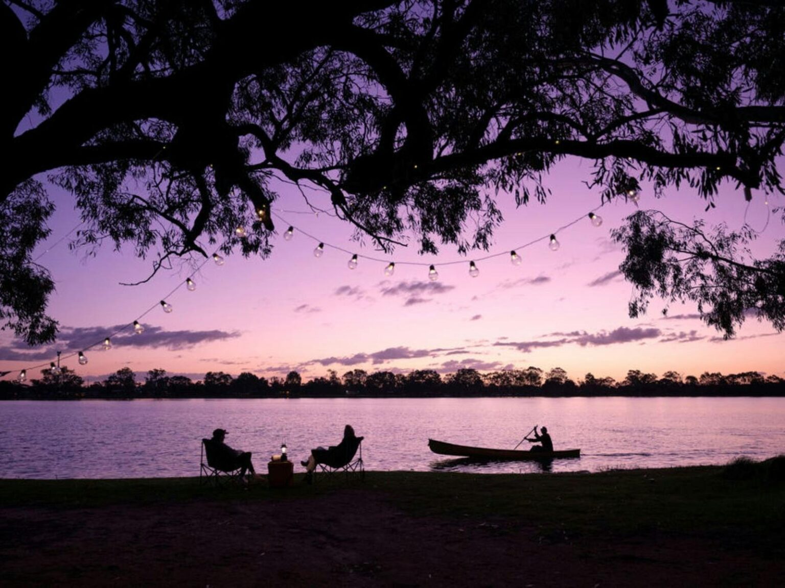 Twilight photo of people sitting on the bank of the lake