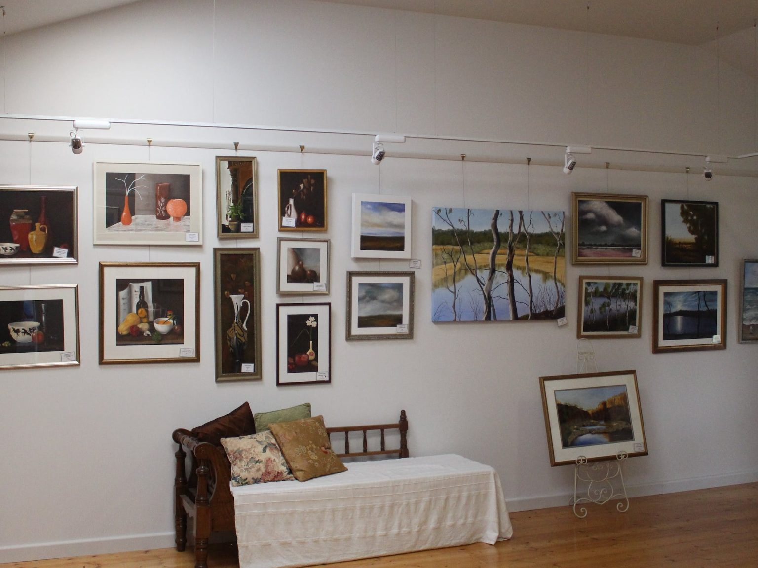 Paintings on the gallery wall including several still life and landscapes