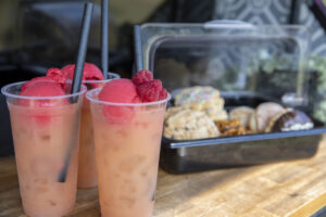 2 drinks and a takeaway tray of delicious treats on a bench