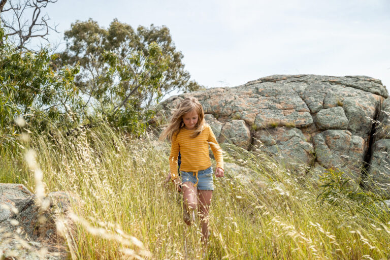 Little girl walking in long grass on Mount Wycheproof