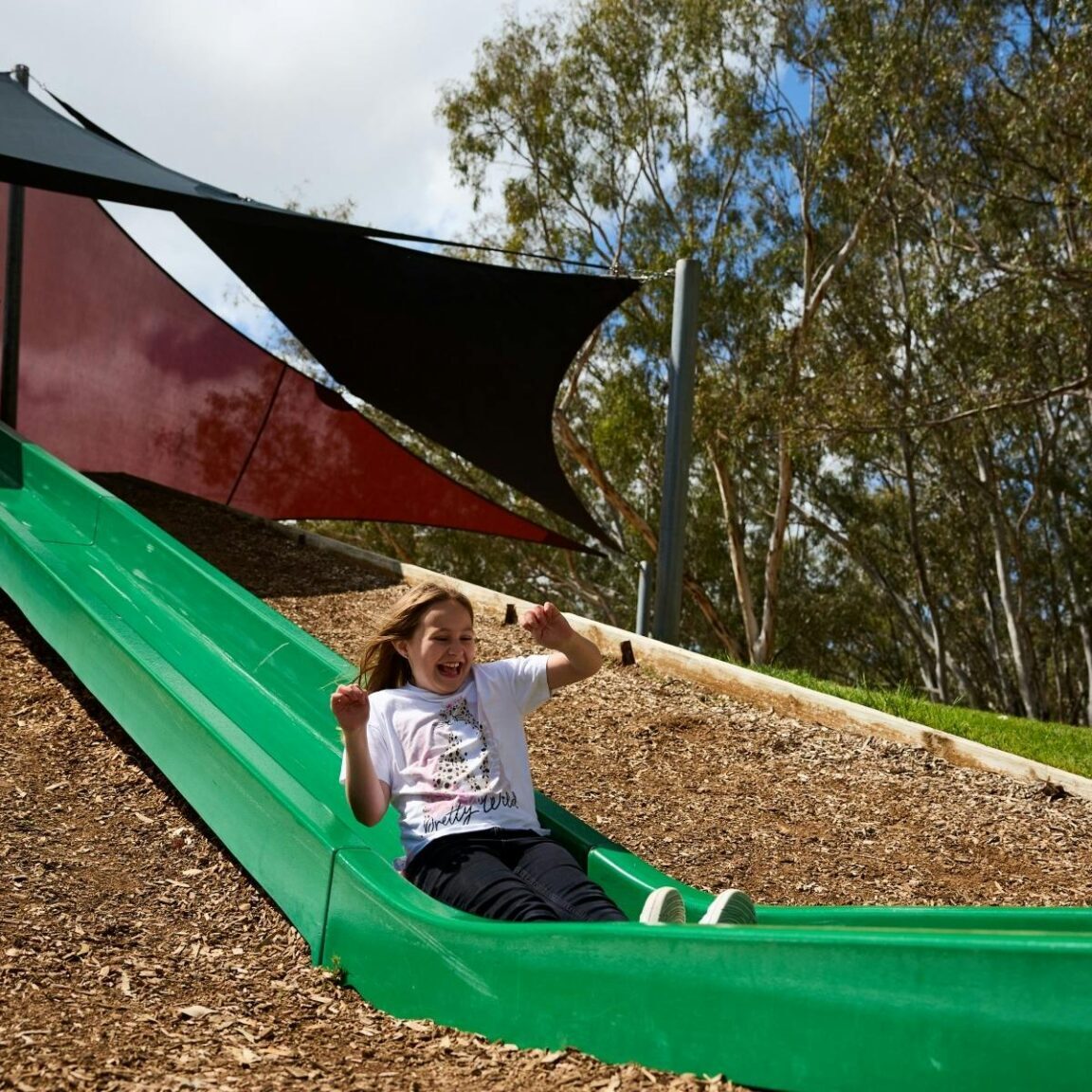 girl sliding down large green slide
