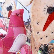 Image of handcrafted fabric pink bird in foreground and a handmade snowman face in background