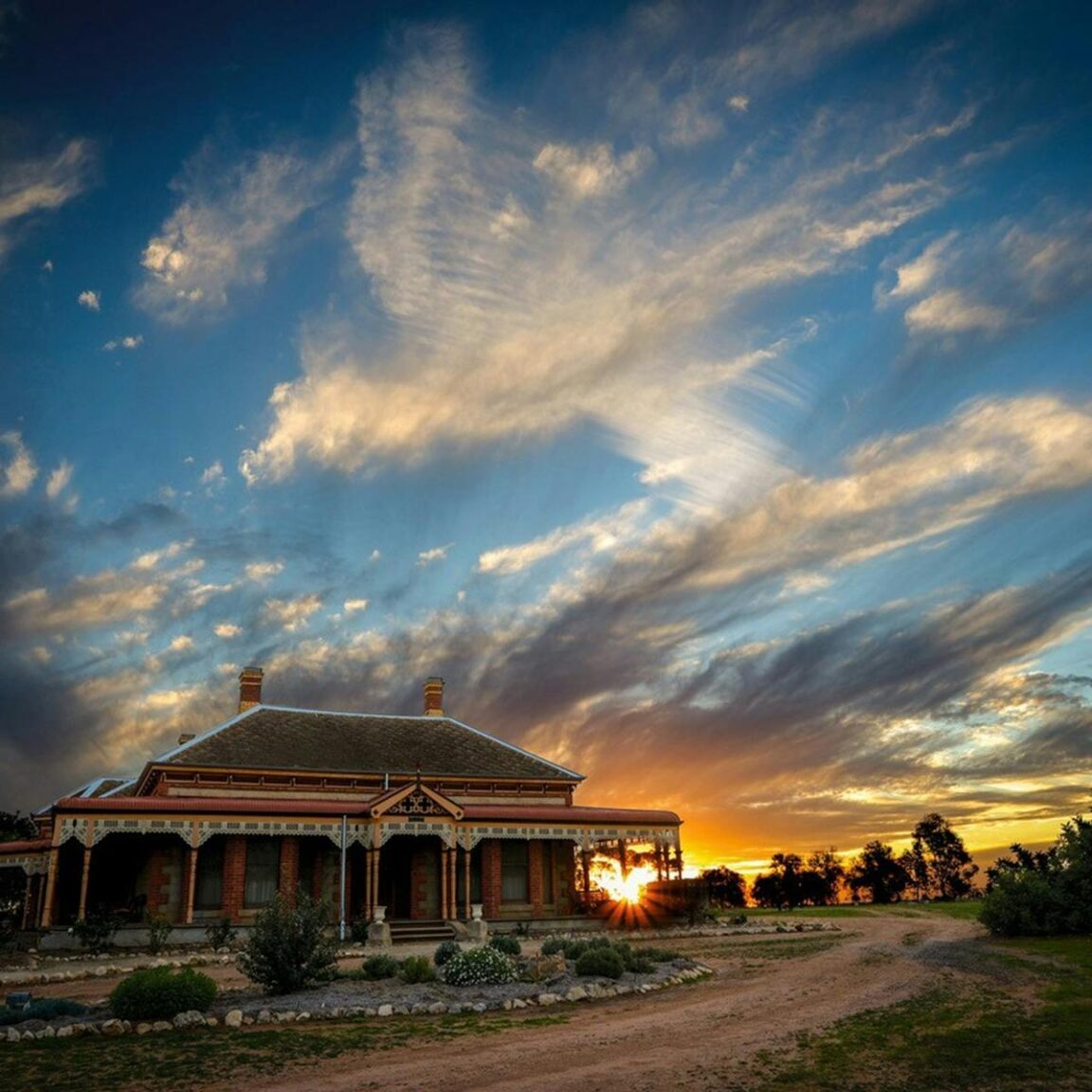 colourful sunset with old homestead and gardens in foreground