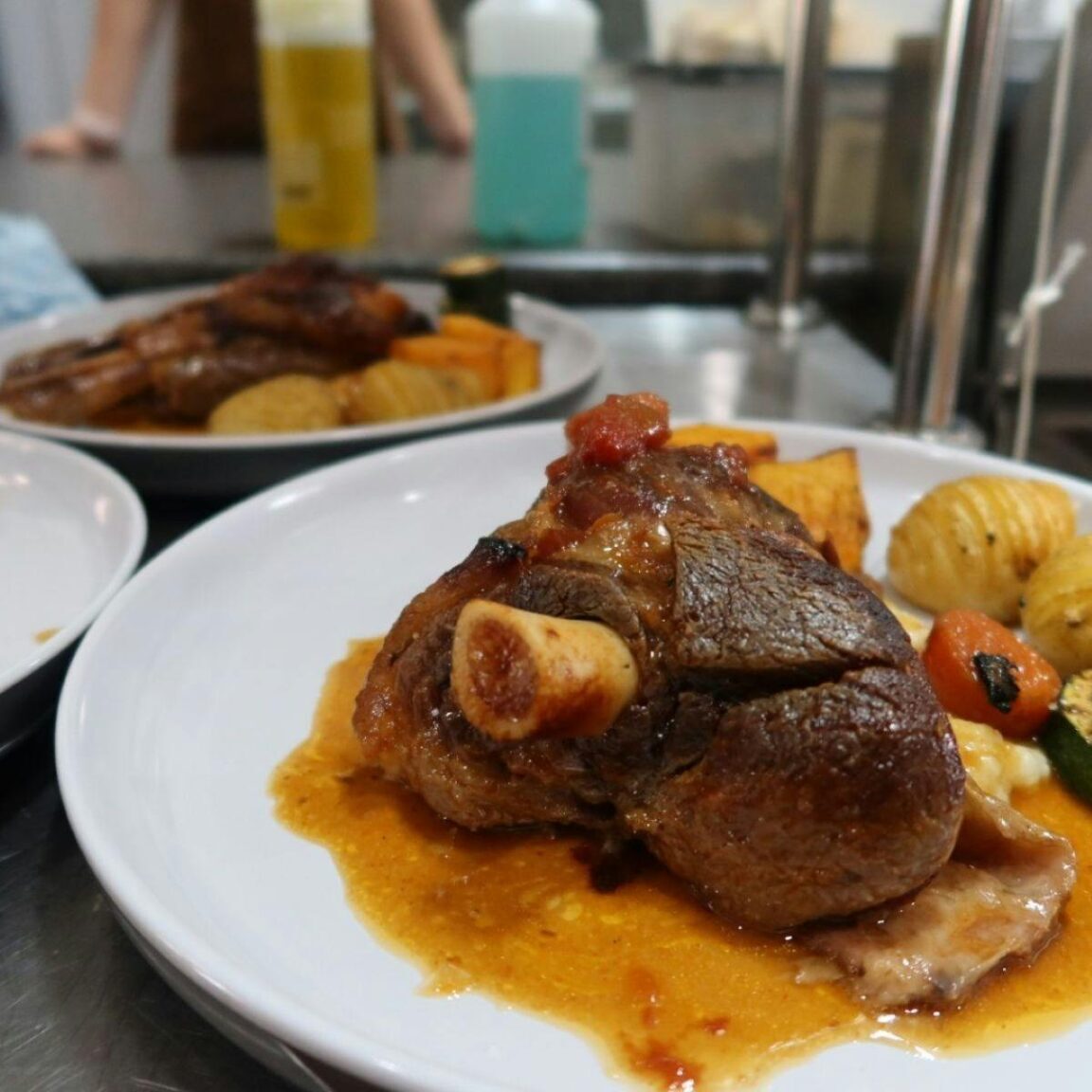 Plates of lamb shanks and vegetables on a large table