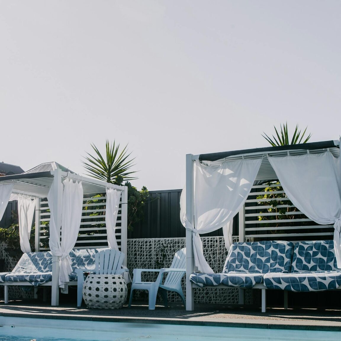 Day beds by sparkling blue pool water.