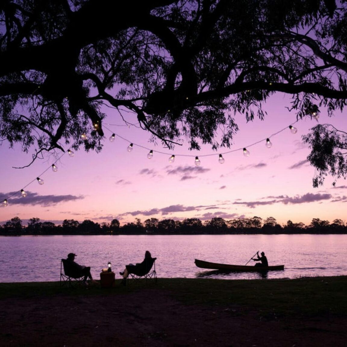 Twilight photo of people sitting on the bank of the lake