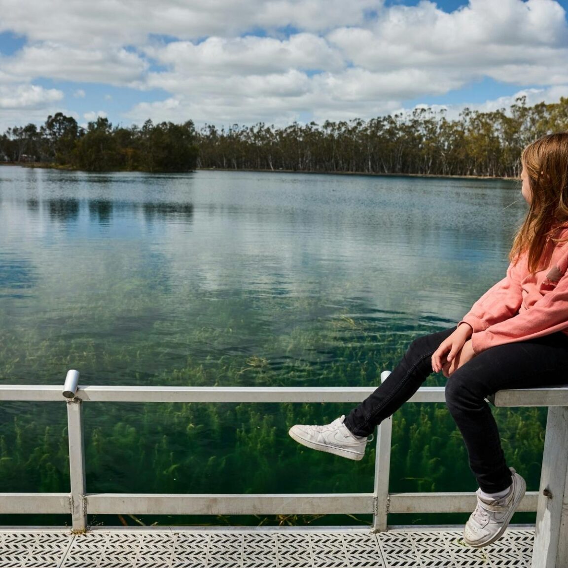 Girl sitting on pontoon overlooking lake