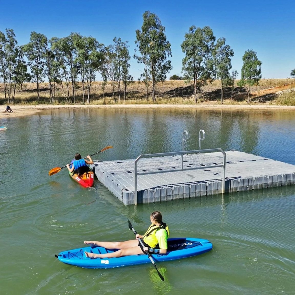 two kayaks around swimming pontoon in lake