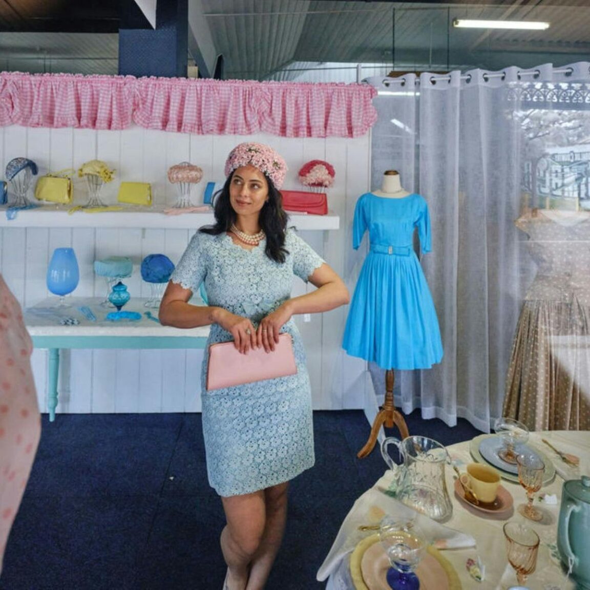 Young person standing in a window display dressed in vintage clothing