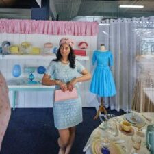 Young person standing in a window display dressed in vintage clothing