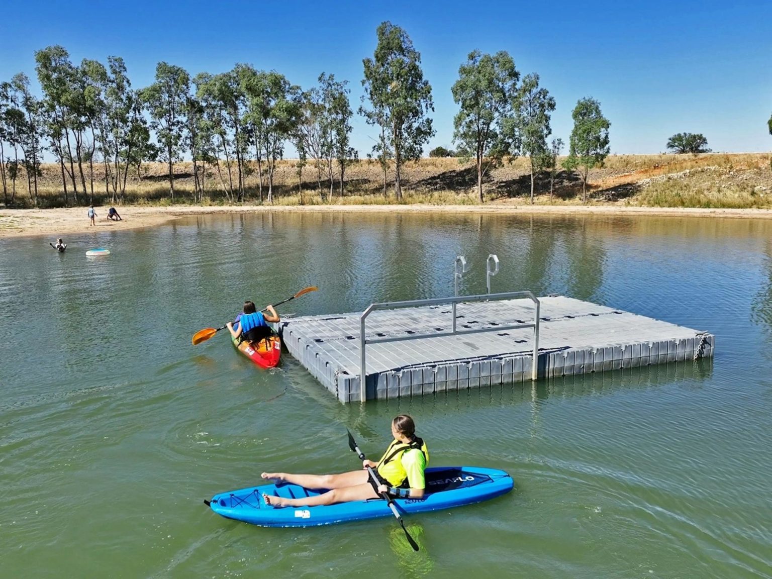 two kayaks around swimming pontoon in lake