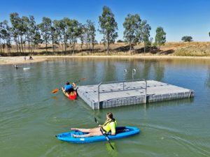 two kayaks around swimming pontoon in lake
