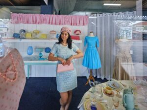 Young person standing in a window display dressed in vintage clothing